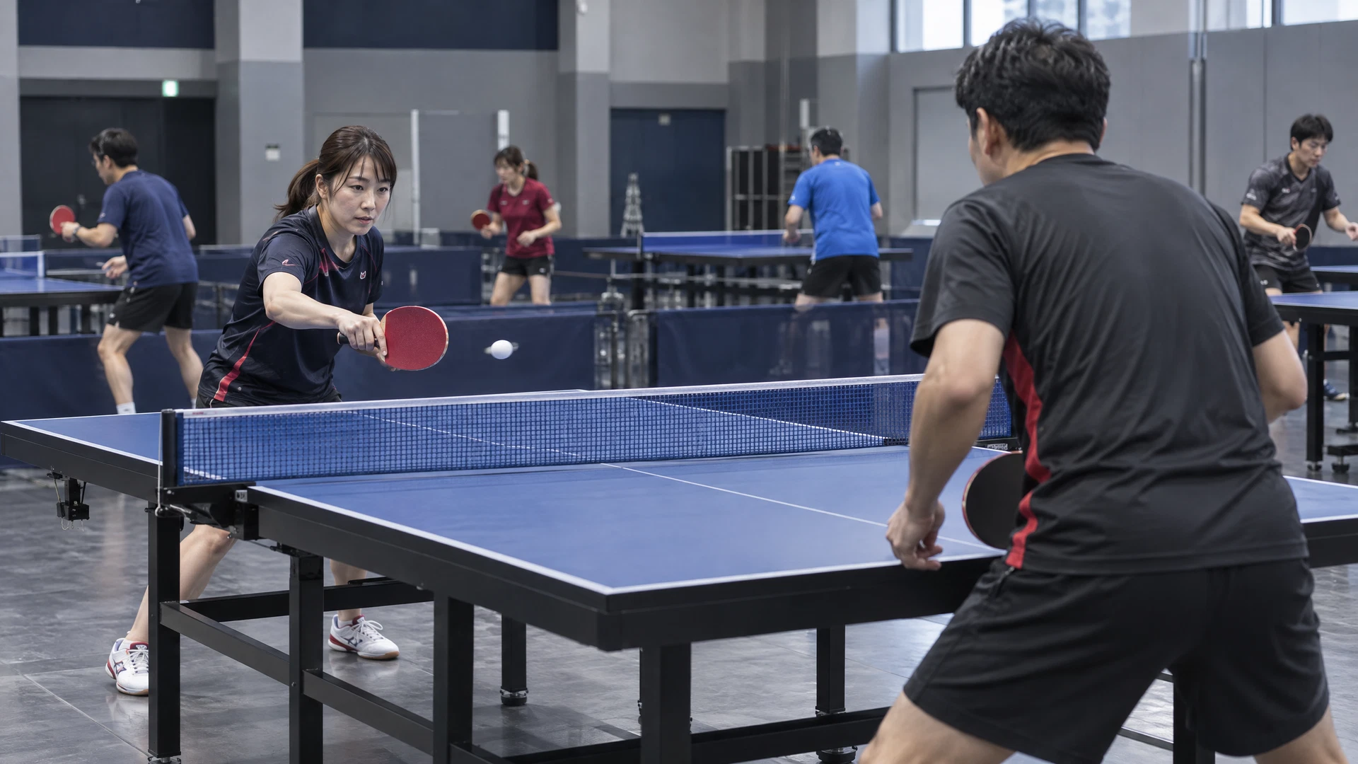 室内卓球場で練習する成人プレーヤー